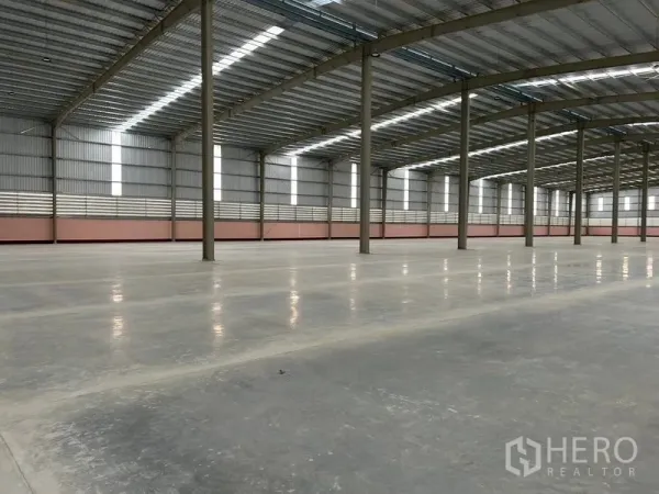 Warehouse for rent in Nikhom Phatthana, Rayong - Expansive warehouse interior featuring a high steel roof, skylights and polished concrete floors.