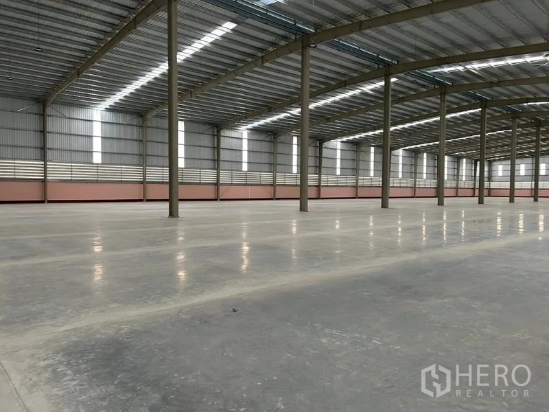 Warehouse for rent in Nikhom Phatthana, Rayong - Expansive warehouse interior featuring a high steel roof, skylights and polished concrete floors.