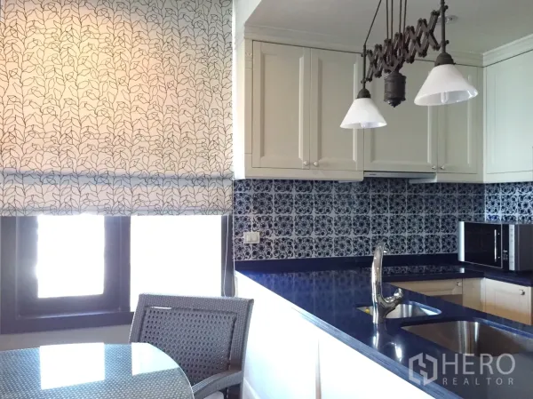 Condominium for rent in Khlong Toei, Bangkok - Bright kitchen with white cabinets, blue patterned tile backsplash, pendant lights and double sink