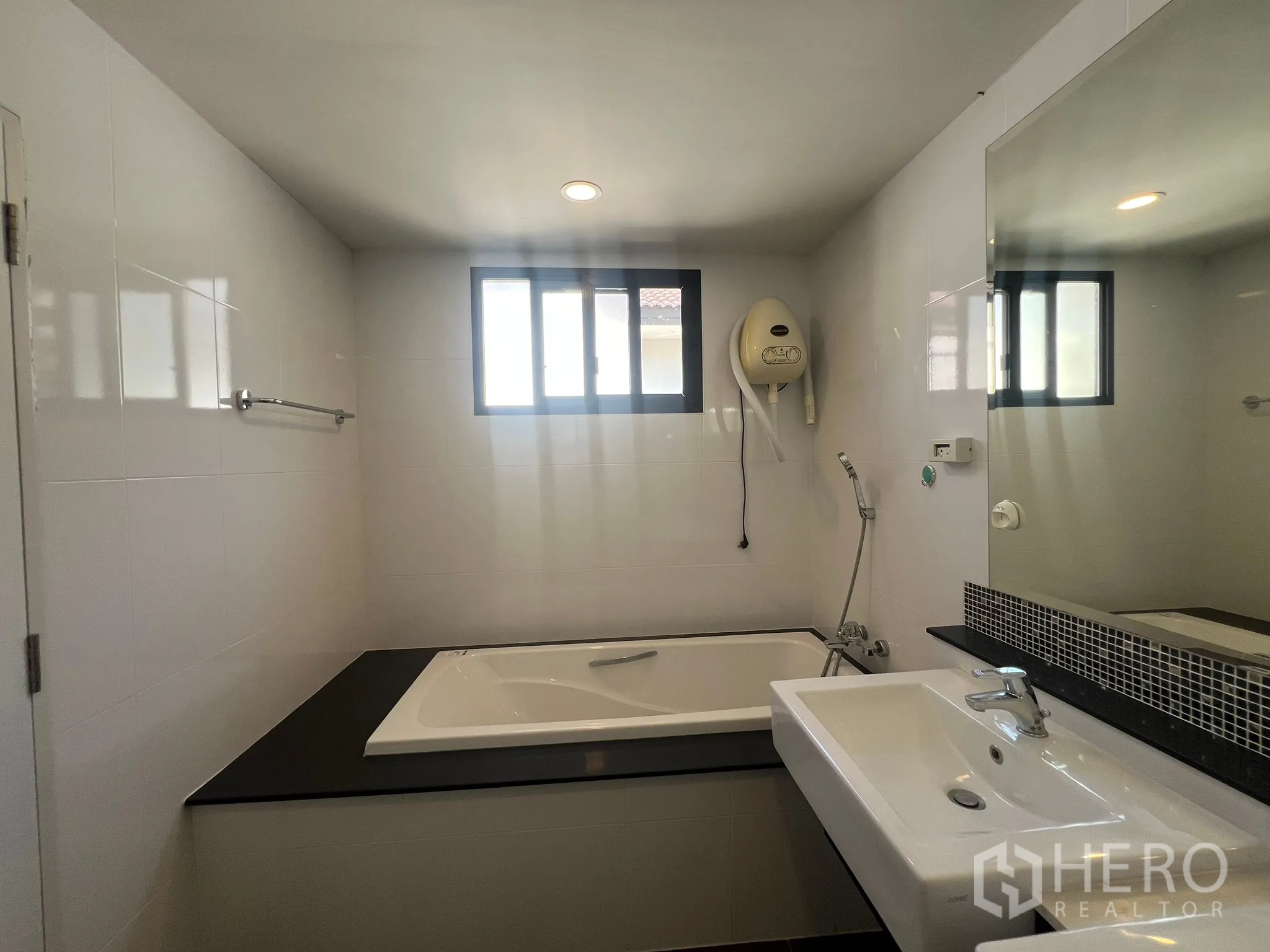 Detached House for rent or sale in Prawet, Bangkok - Bathroom with bathtub under window and vanity sink.