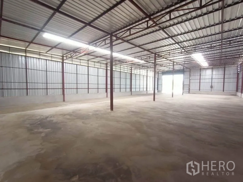 Warehouse for rent in Mueang Samut Sakhon, Samut Sakhon - Spacious warehouse interior with steel columns, high roof, skylight panels and concrete floor.