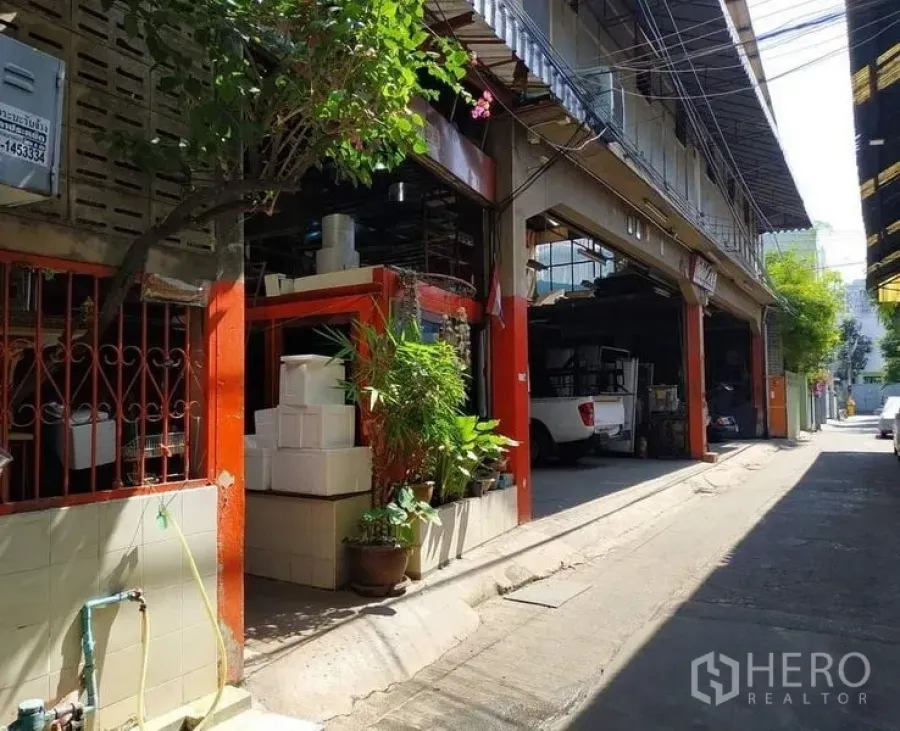 Warehouse for rent in Yan Nawa, Bangkok - Side facade of the warehouse with orange columns, potted plants and lane access in Yan Nawa.