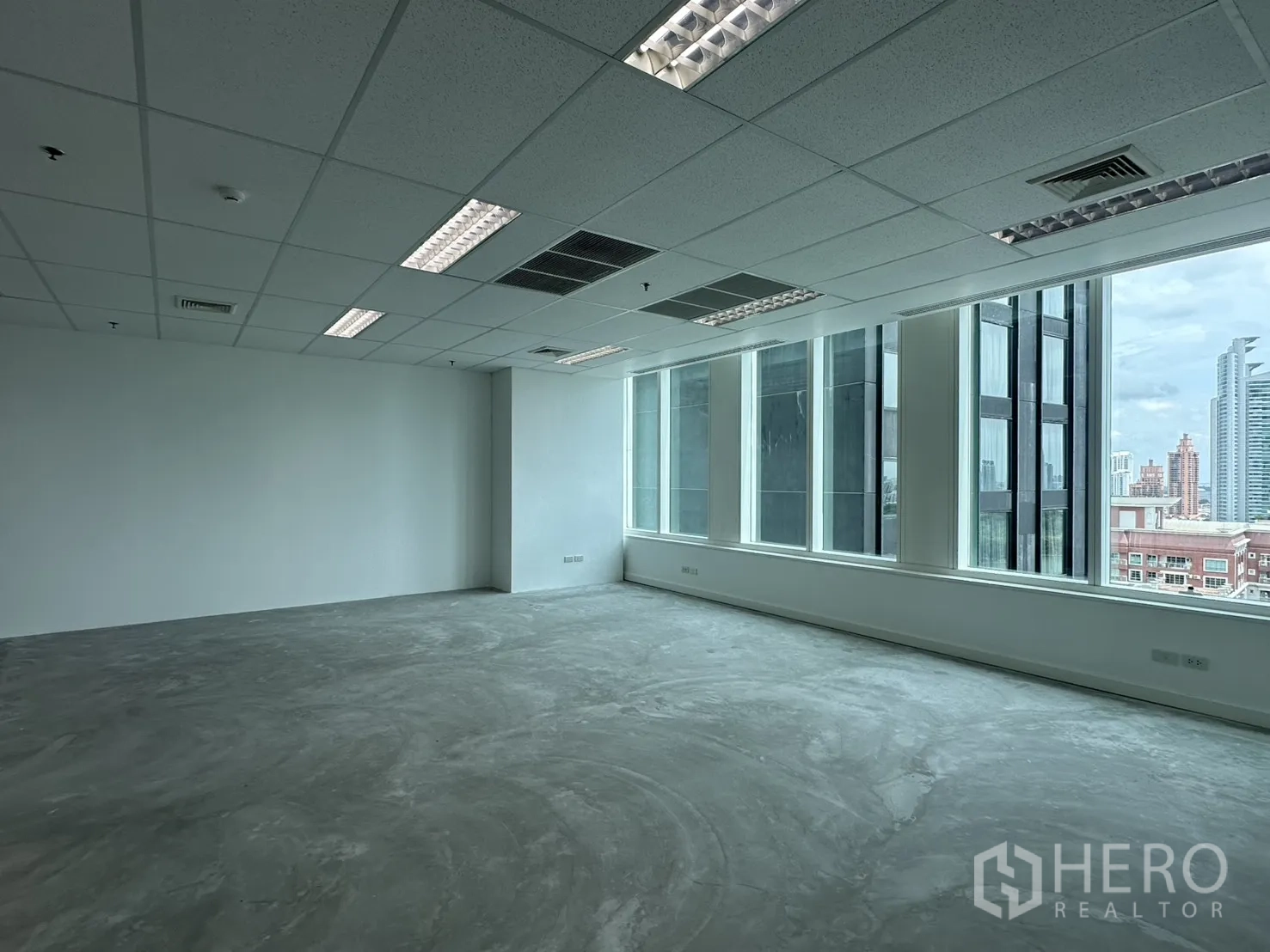 Office Space for rent in Watthana, Bangkok - Open-plan office with large windows, suspended ceiling lights, and city skyline views.