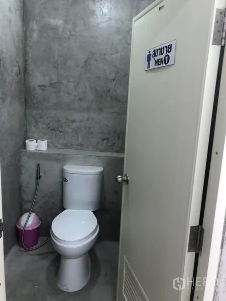 货栈 出租在Bang Yai, Nonthaburi - 清洁的男厕，坐便器、喷枪与清水混凝土墙面。