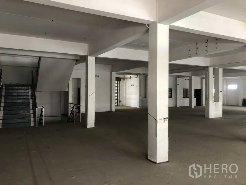 Factory for rent in Prawet, Bangkok - Open production area with columns and stair access between floors.