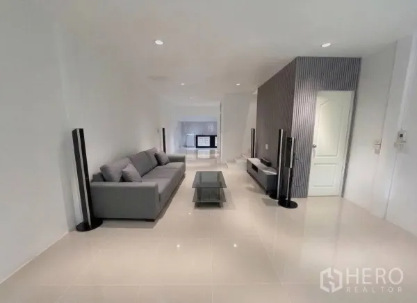 Townhouse for rent in Phra Khanong, Bangkok - Bright living room featuring a gray sofa, glass coffee table and TV console.