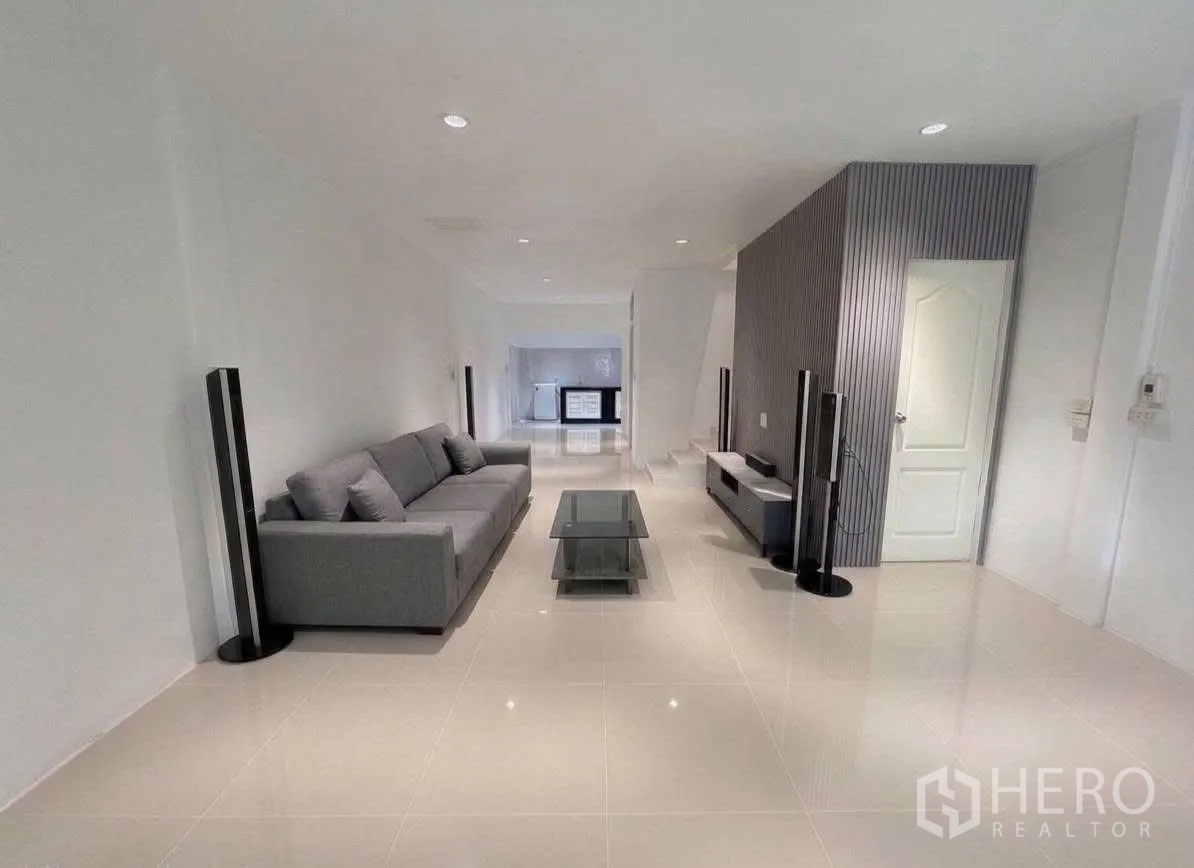 Townhouse for rent in Phra Khanong, Bangkok - Bright living room featuring a gray sofa, glass coffee table and TV console.