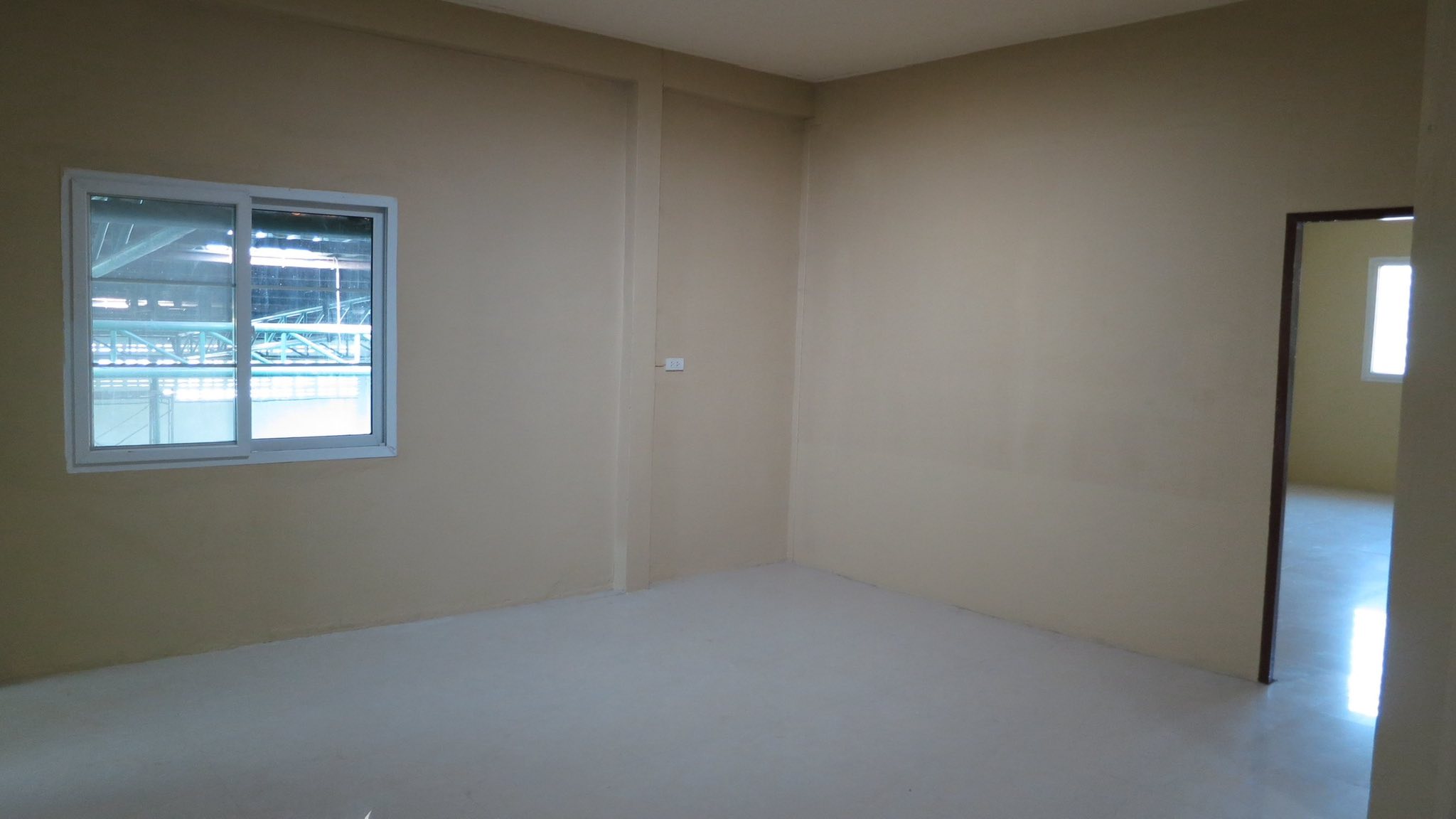 Warehouse for rent in Wang Thonglang, Bangkok - Bright office room with a sliding window overlooking covered structures.