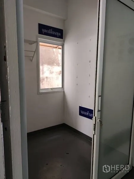 Warehouse for rent in Bueng Kum, Bangkok - Small changing room with window and shelf, grey floor.