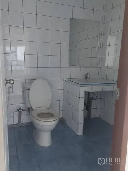 Office Space for rent in Pathum Wan, Bangkok - Compact tiled washroom with toilet, vanity and mirror.