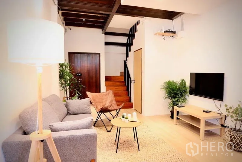 Townhouse for rent in Sathon, Bangkok - Modern living room with sofa, TV, staircase and greenery