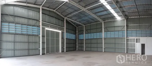 Warehouse for rent in Khlong Luang, Pathum Thani - Open clear-span warehouse hall with skylights, louvered vents and a smooth concrete floor.