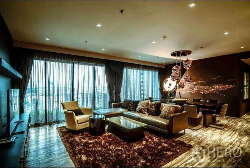 Condominium for rent or sale in Khlong Toei, Bangkok - Spacious living and dining area with floor-to-ceiling windows, plush rug and contemporary lighting.