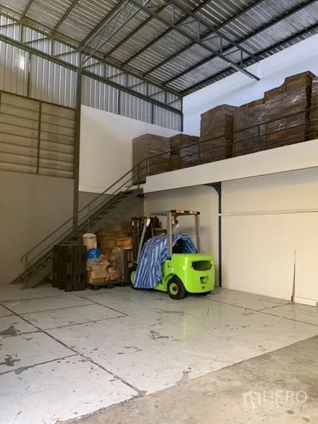 Warehouse for rent in Bang Kapi, Bangkok - High-bay warehouse section with mezzanine storage, metal staircase and forklift access.