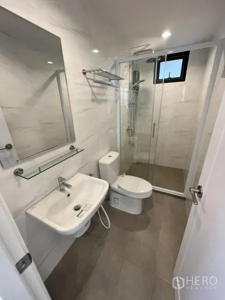 Detached House for rent in Phaya Thai, Bangkok - Compact bathroom with frameless glass shower and wall-mounted vanity.