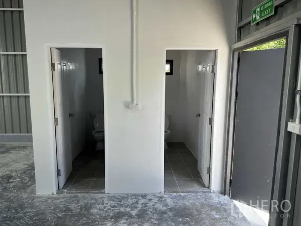 Warehouse for rent in Pak Kret, Nonthaburi - Two on-site restrooms with tiled floors and white doors inside the warehouse.