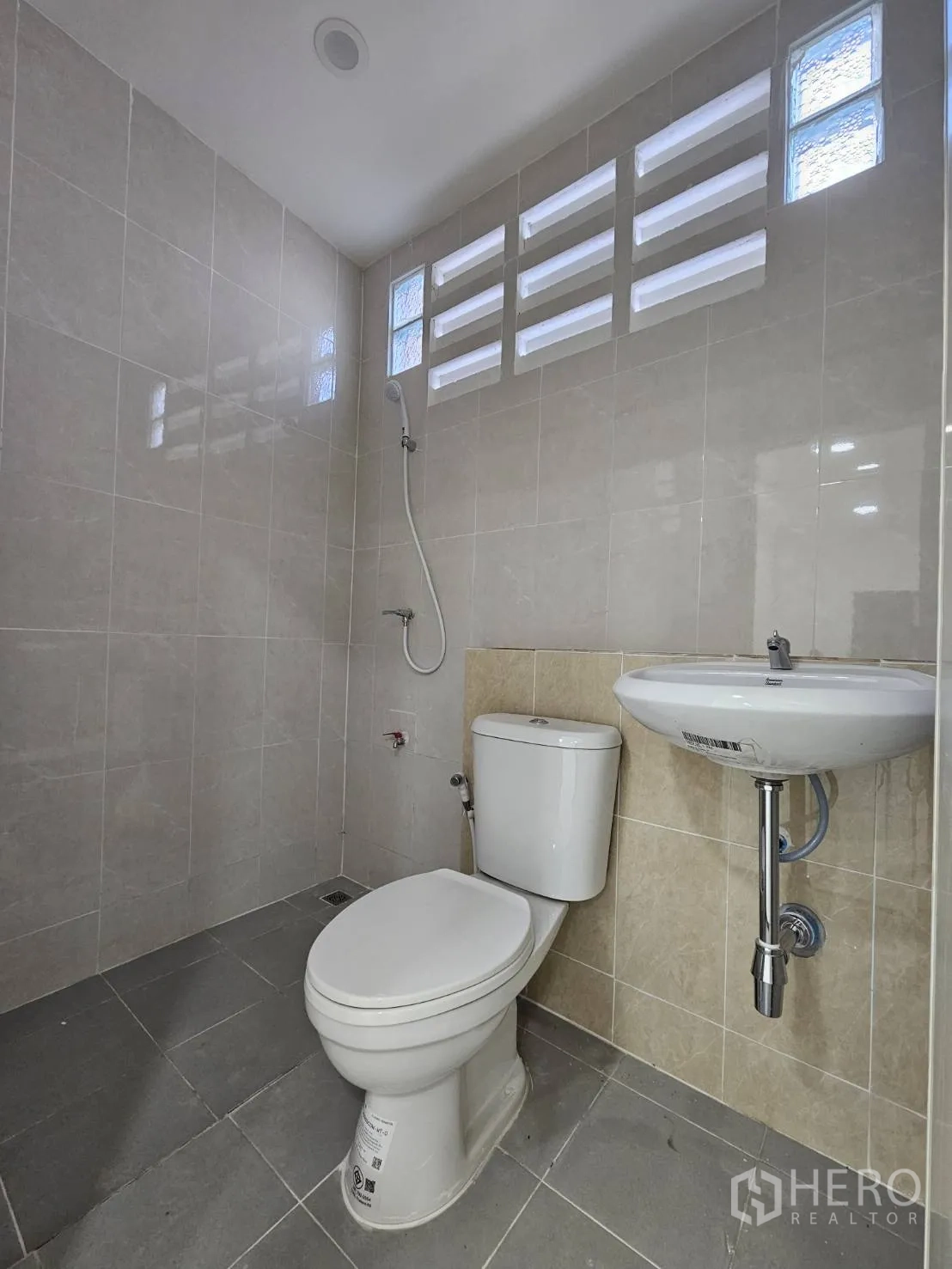 Warehouse for rent in Mueang Samut Prakan, Samut Prakan - Modern restroom with toilet, wall-mounted sink, and shower set.