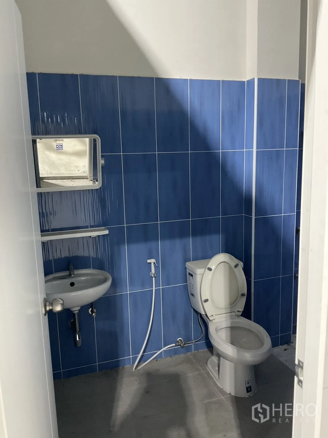 Warehouse for rent in Bang Bua Thong, Nonthaburi - Warehouse restroom with sink, bidet spray, and toilet with blue tiling.