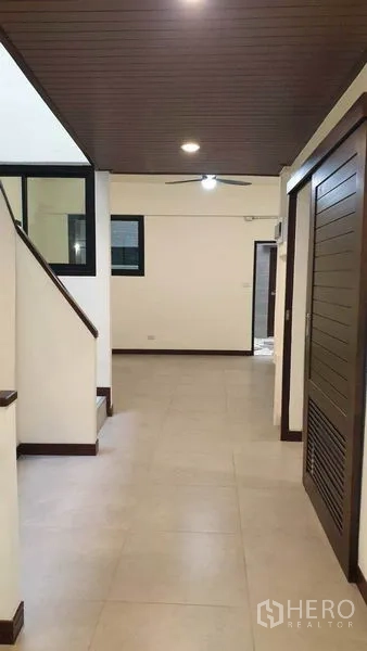 Townhouse for rent or sale in Khlong Toei, Bangkok - Hallway with staircase and wood ceiling panels leading to upper floors.
