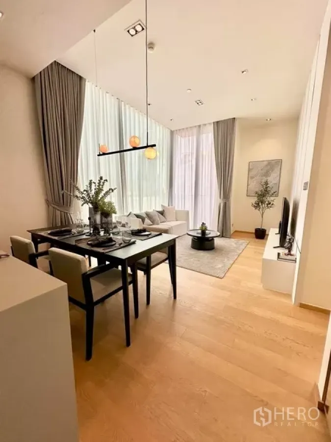 Condominium for rent in Pathum Wan, Bangkok - Bright living and dining area with floor-to-ceiling windows, modern pendant light, and light wood flooring.