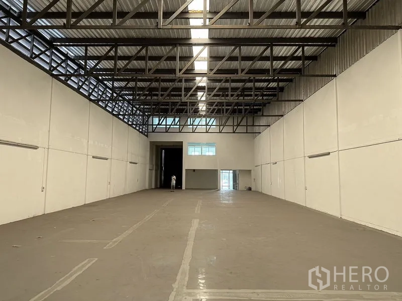 Factory for rent in Bang Sao Thong, Samut Prakan - Deep warehouse interior facing the loading entrance with office windows at the far end.
