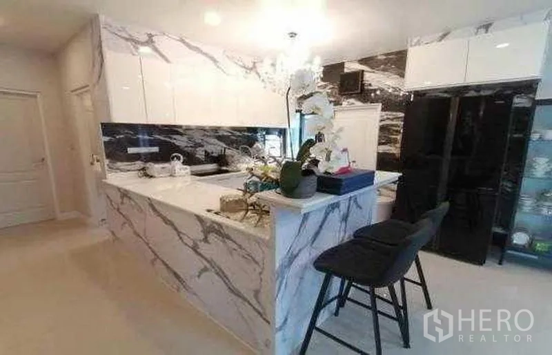 Detached House for sale in Bang Phli, Samut Prakan - Modern kitchen with marble countertops, breakfast bar, white cabinetry and black appliances.