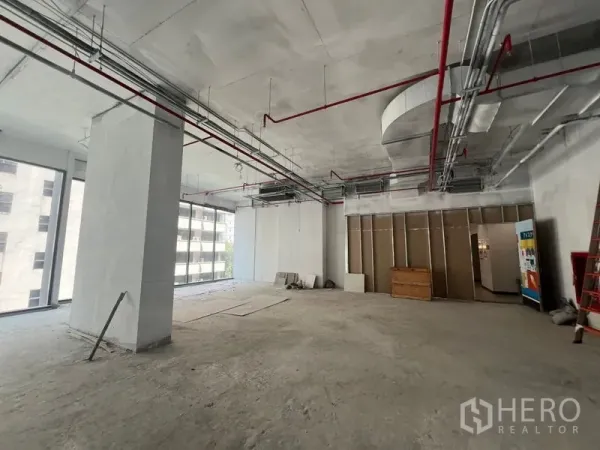 Retail Space for rent in Khlong Toei, Bangkok - Spacious retail area with wraparound glazing, visible HVAC and sprinkler system, plus a partitioned back-of-house zone.