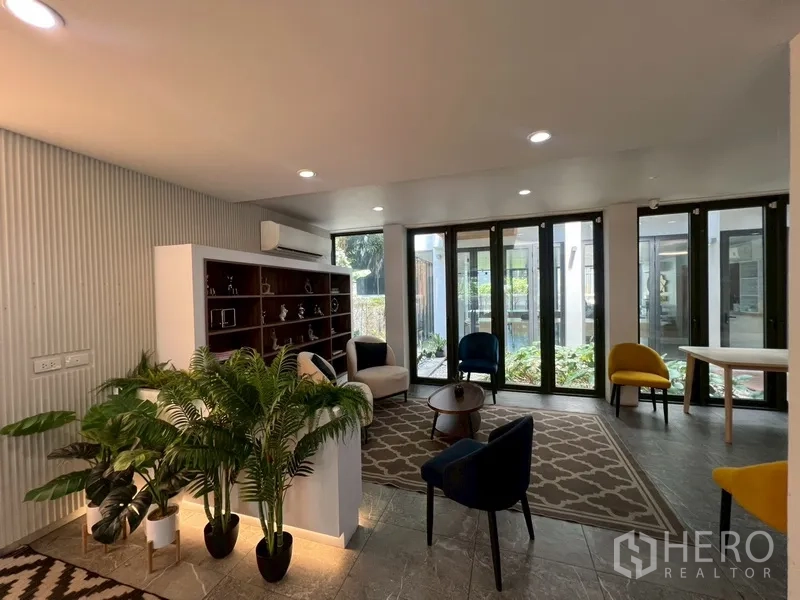 Home Office for rent or sale in Phra Khanong, Bangkok - Reception lounge with built‑in bookshelf and garden-facing windows.