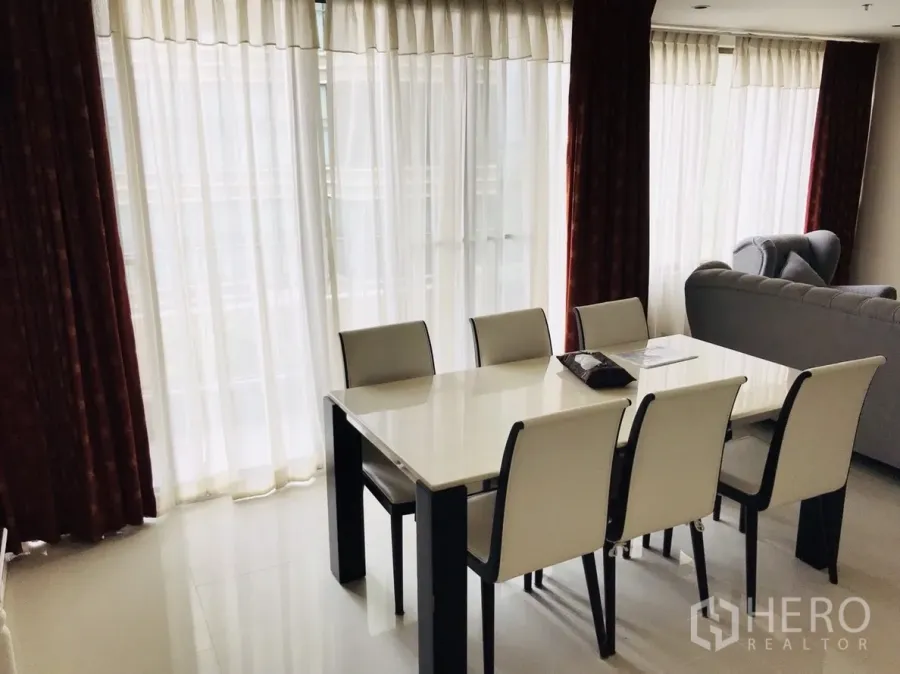 Condominium for rent or sale in Khlong Toei, Bangkok - Bright dining area with a six-seat table beside floor-to-ceiling windows and sheer curtains.