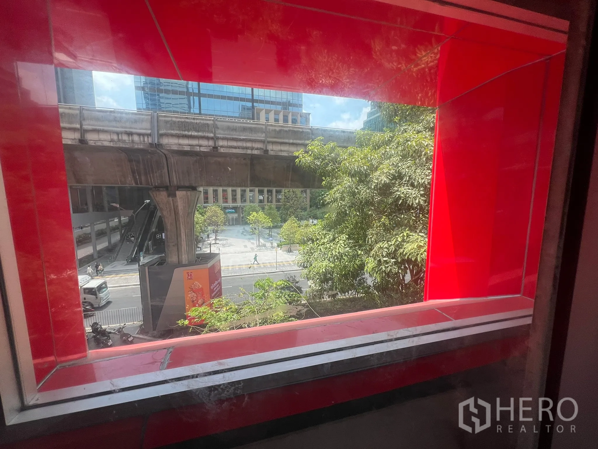 Retail Space for rent - Window view toward the BTS Skytrain track and city street lined with trees.