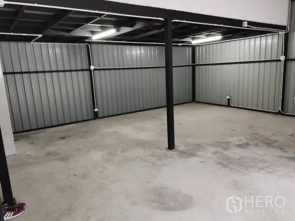 Warehouse for rent in Suan Luang, Bangkok - Spacious storage area with metal wall panels, central support post, and overhead lighting.