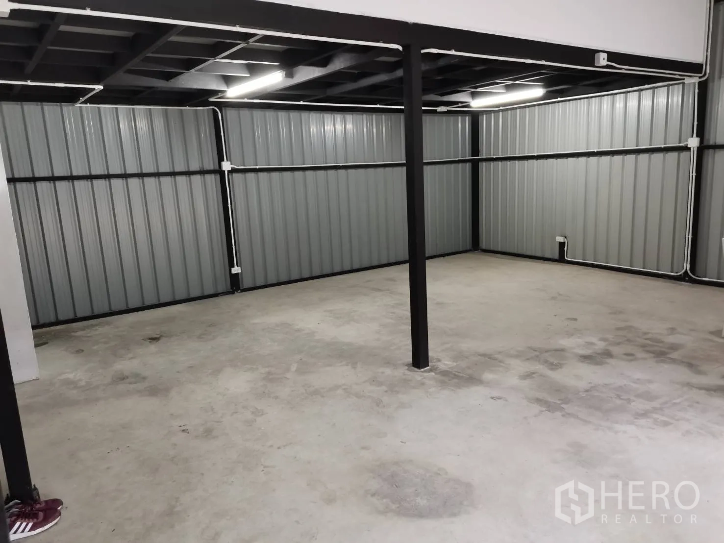 Warehouse for rent in Suan Luang, Bangkok - Spacious storage area with metal wall panels, central support post, and overhead lighting.