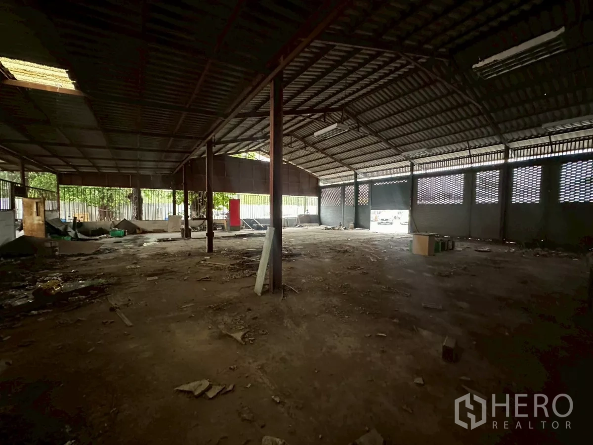 Warehouse for rent or sale in Yan Nawa, Bangkok - Deep warehouse space with steel columns and partial dirt floor awaiting fit-out.