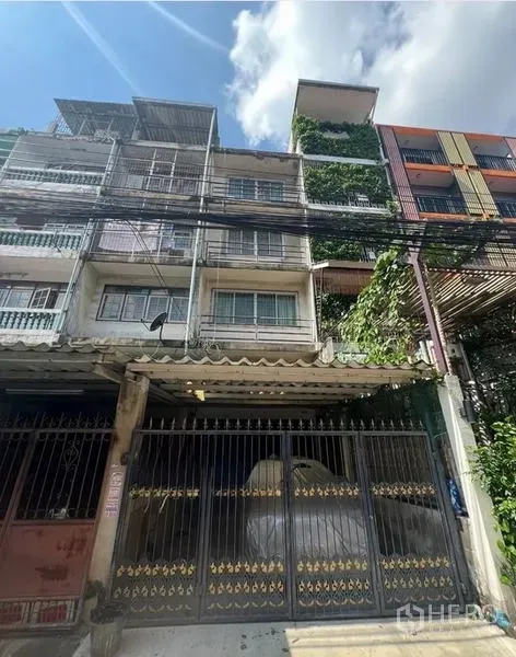 Shophouse for sale in Phra Khanong, Bangkok - Four-storey shophouse facade with metal gate, balconies and covered parking in Bang Chak area.