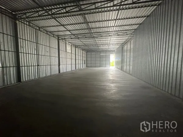 Warehouse for rent in Wang Thonglang, Bangkok - Long open-plan warehouse with corrugated metal walls, polished concrete floor, and natural light at the wide end door.