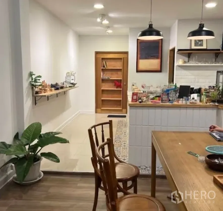 Shophouse for rent in Watthana, Bangkok - Warmly lit shophouse interior with wooden counter, pendant lights and seating.