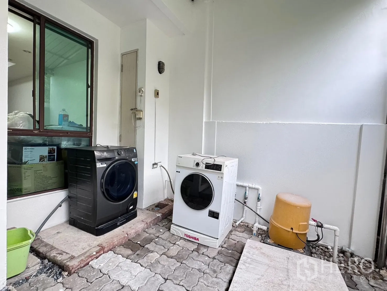 Townhouse for rent in Phra Khanong, Bangkok - Covered outdoor laundry area with two washing machines and a water pump.
