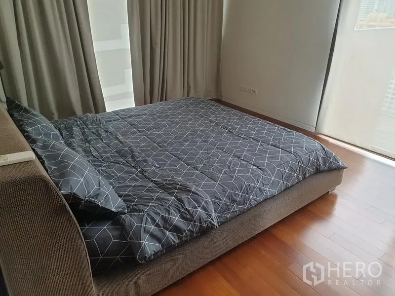 Condominium for rent in Pathum Wan, Bangkok - Cozy bedroom with double bed, wood flooring and full-height windows with blackout curtains and city outlook.