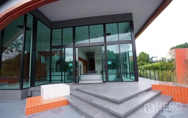 Standalone for rent in Bang Na, Bangkok - Main entrance steps leading to tall glass doors and a covered porch.
