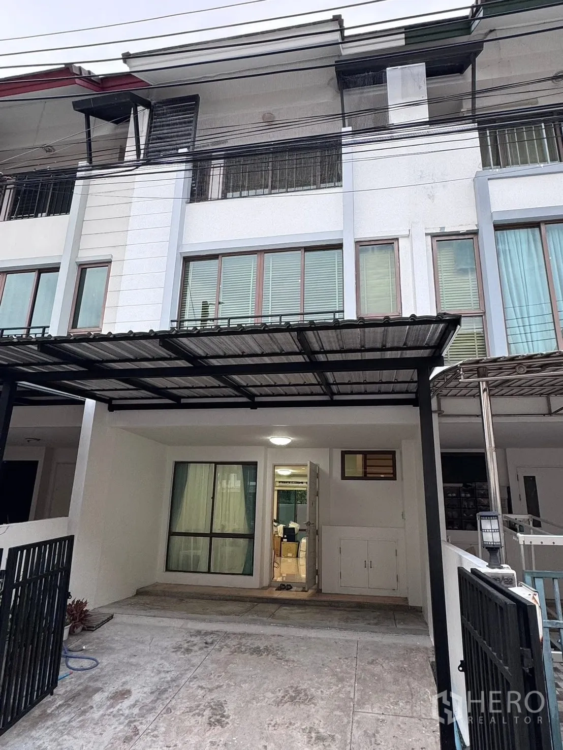 Townhouse for rent in Phra Khanong, Bangkok - Townhouse exterior facade with gated carport and balconies.