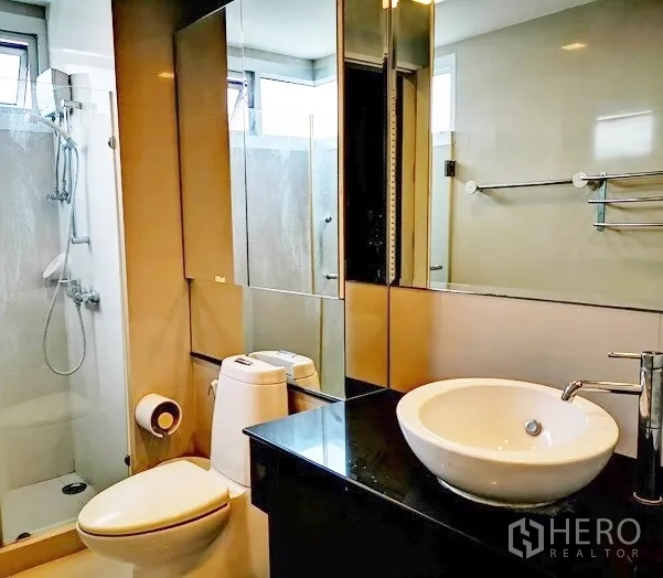 Condominium for rent in Khlong Toei, Bangkok - Contemporary bathroom with walk‑in shower, vessel sink and mirrored storage.