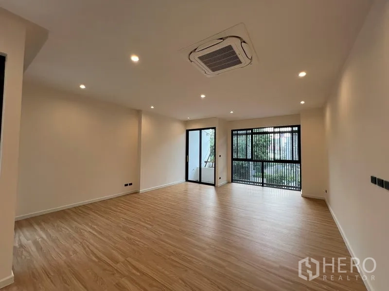 Home Office for sale in Phra Khanong, Bangkok - Spacious upper floor room with cassette air‑con, wood flooring and large windows to a balcony.