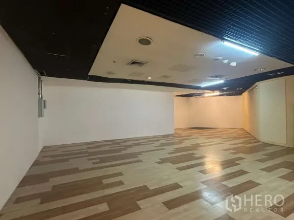 Retail Space for rent - Spacious open-plan retail unit with wood-pattern flooring and black drop ceiling lighting.