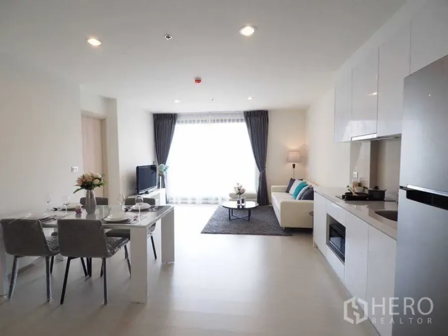 Condominium for rent in Khlong Toei, Bangkok - Open-plan living, dining and kitchen area facing a large bright window