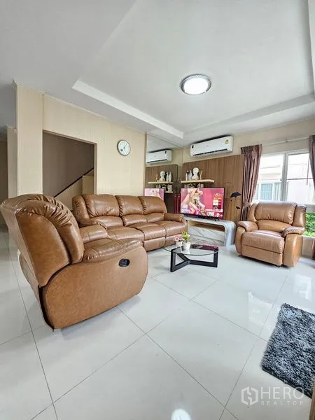 Detached House for rent - Airy living room with brown leather sofa set, white tile flooring and media wall.