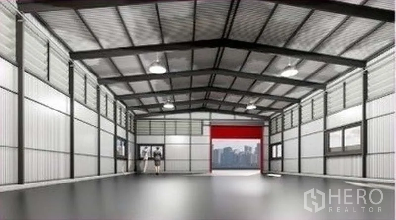 Warehouse for rent in Lat Phrao, Bangkok - Spacious warehouse interior with high steel truss ceiling, LED lighting, windows, and a red roller door at the far end.