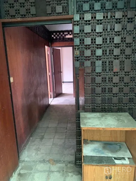 Shophouse for rent in Watthana, Bangkok - Corridor with patterned block wall and doorways leading to side rooms.