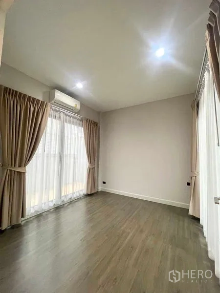 Detached House for sale in Bang Kruai, Nonthaburi - Upstairs bedroom with wood flooring, corner windows, soft drapes and air conditioning.