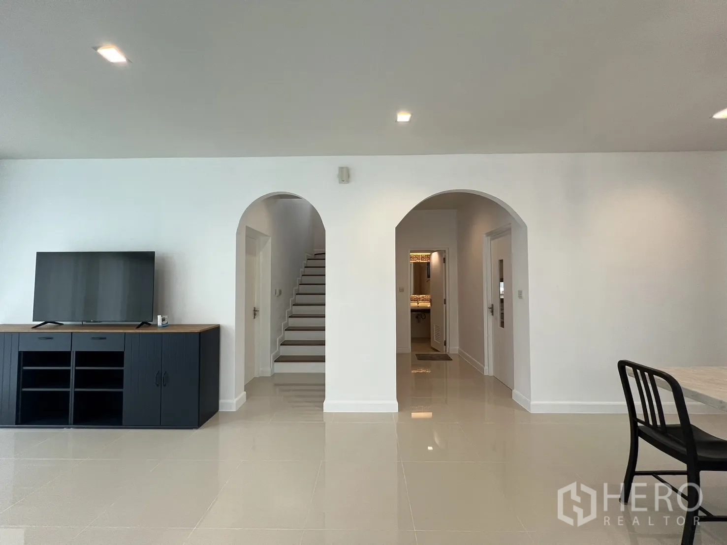 Detached House for rent in Bang Kapi, Bangkok - Living space showing central staircase through an arch and a low TV cabinet.
