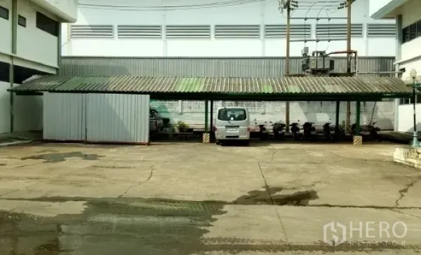Factory for sale in Bang Phli, Samut Prakan - Covered parking shed with a van and motorbike spaces inside the factory yard.